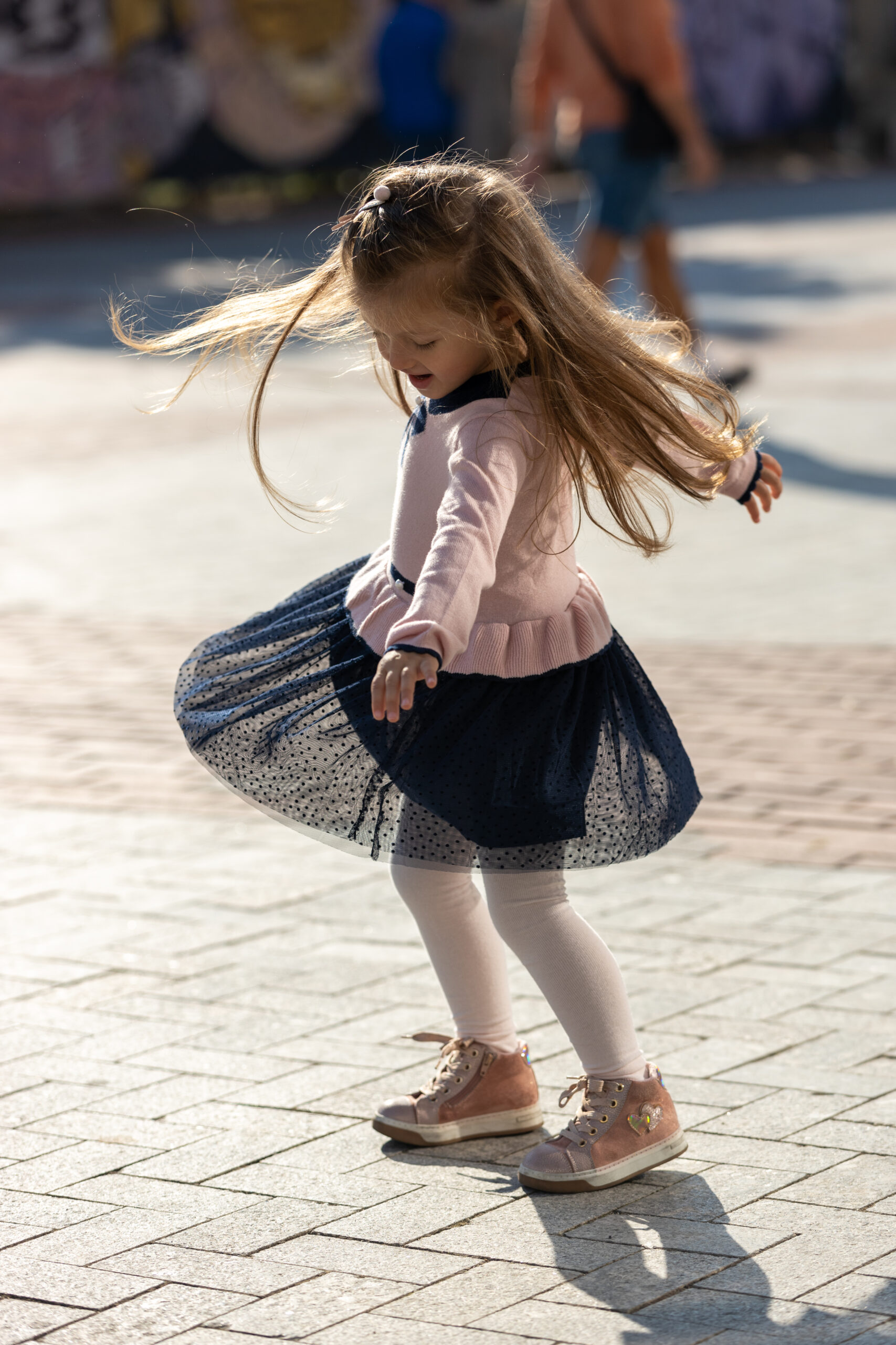 Little girl with long blonde hair dancing on the street